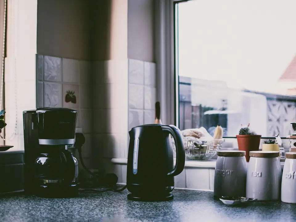Küchenarbeitsplatte mit Kaffeemaschine, Wasserkocher und Vorratsdosen vor einem Fenster